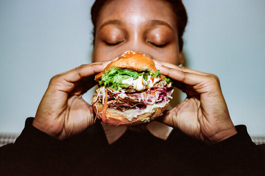 Close-up of woman taking bite out of burger