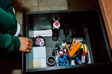 Hand of person opening office drawer with stationery supplies