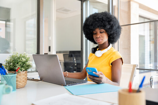 Office worker managing projects using laptop and smartphone