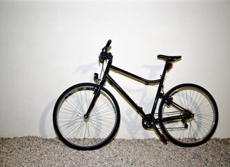 Vintage-style bicycle parked outside a house on gravel ground, with clear copy space on the side. The warm and soft lighting enhances the rustic charm of the scene.