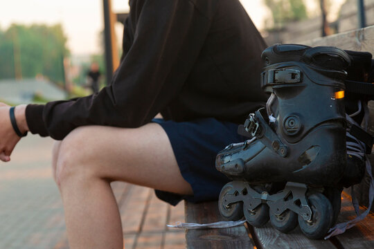 Teenager resting on bench with inline skates after skating session