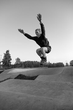 Teenager performing jump with inline skates at skatepark