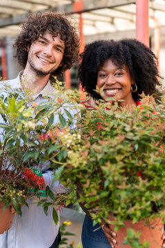 Garden center workers holding plants smiling at the camera