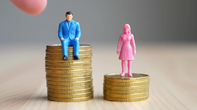 Man and Woman Figurines on Different Gold Coin Stacks Representing Pay Inequality
