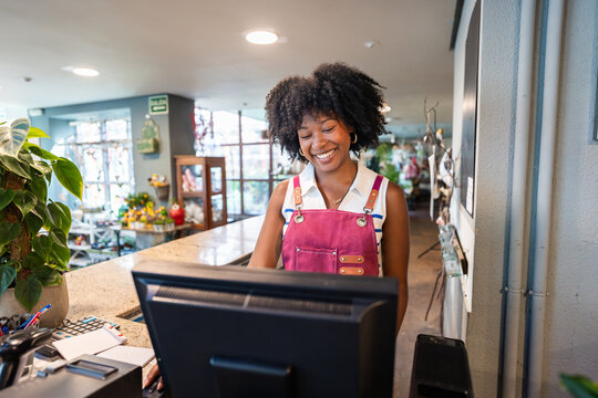 Smiling florist processing an order at the computer in a flower shop
