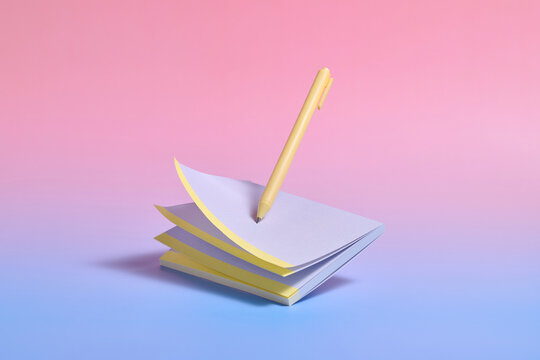 A pen poised above a stack of notepaper