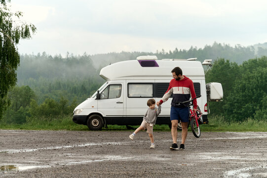 Father and son returning to camper van after biking adventure