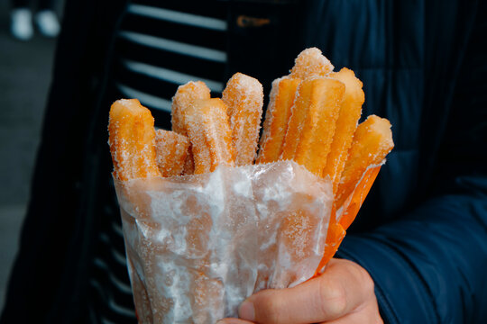 man with a paper bag with churros in his hand