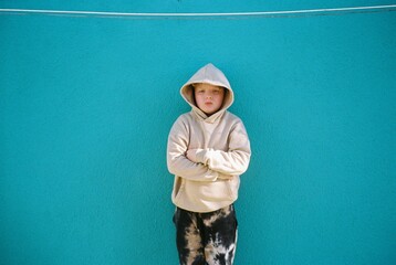 Child in Hoodie Against blue Wall

