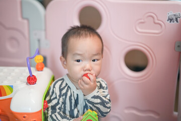 A Chinese family gathers in their living room as a one-year-old baby plays inside a child safety fence, surrounded by cozy furniture and warm light, enjoying the moment. Spring. Shanghai. China.