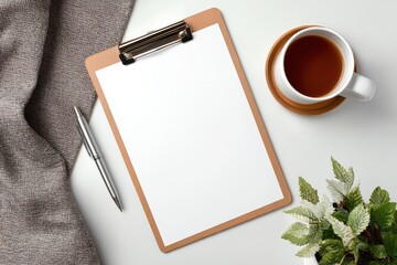 Home office desk workspace with clipboard and blank paper, pen, tea cup and plant on white background, flat lay, top view, copy space