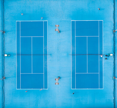 Aerial View of Two Blue Tennis Courts with Players