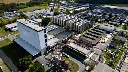Vista aérea de um moderno complexo industrial com silos e estruturas metálicas, representando a...