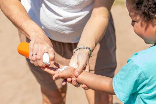 Applying Sunscreen on Child at Beach During Summer Day