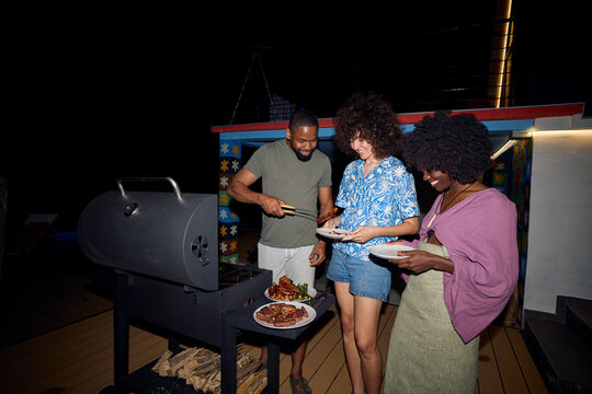 Man serves food from the grill to his friends