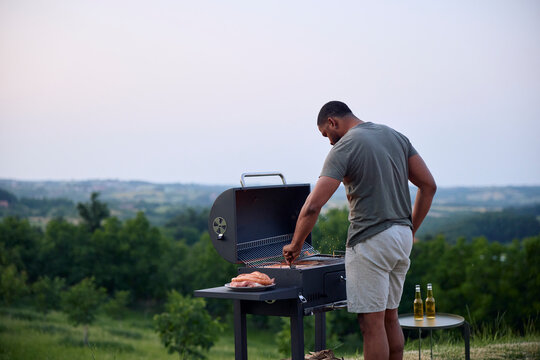 Man prepares a barbecue at dusk