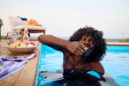 Woman eats fruit in the pool