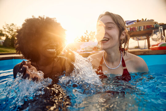 Women are having fun in the pool at sunset
