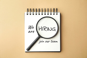 We are hiring, join our team. Notebook with inscription and magnifying glass on beige background,...