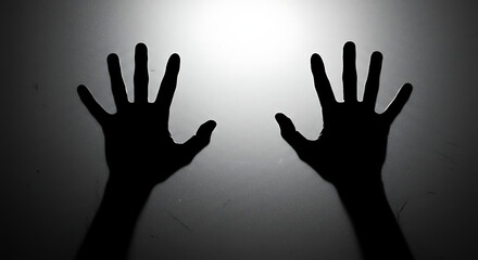 Mysterious silhouette of a person's hands against a glowing background, a concept of fear, horror, and being lost