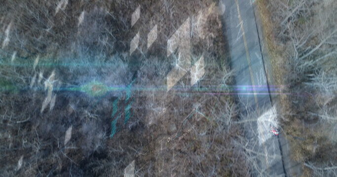 Cycling teenage boy wearing red jacket riding along rural road, with digital overlay, copy space - Powered by Adobe