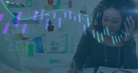 Writing in notebook woman wearing headset analyzing laptop chart overlay in home office, copy space