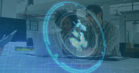 Discussing colleagues reviewing project data on laptop in open-plan office, with holographic globe