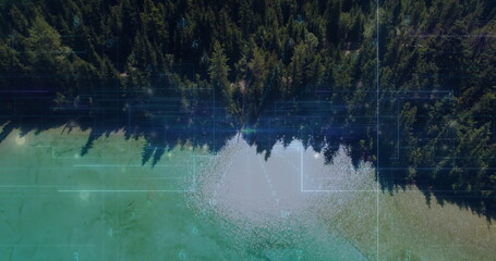 Evergreen forest meeting turquoise lake in remote aerial view, with grid and binary code overlay