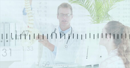 Explaining doctor in white coat demonstrating spine model to patient in clinic, with palm plant