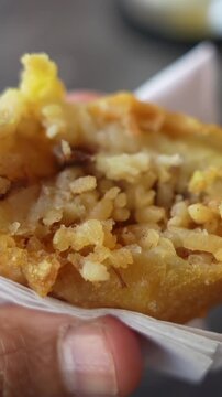 Savor the crispy texture of a papa rellena in this vertical video close-up. The golden-brown crust and rich potato filling are captured in detail, perfect for social media stories.