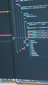 Close-up of coding on dual screens featuring JavaScript. Bright, focused lighting enhances the text details. Perfect for vertical video in mobile and social media.