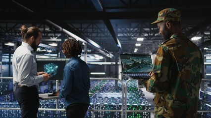 Military technician in data center monitoring warfare drone telemetry on laptop dashboard. IT specialist in army server room using tactical interface on notebook to support aerial operations
