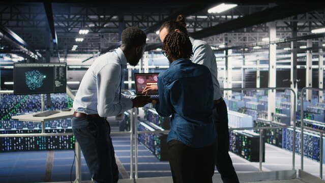 Worried workers trying to fix hacked infrastructure systems. Panicked engineers in data center react to ransomware warning on laptop screen, scrambling to launch emergency response protocol,