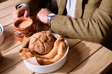 Unrecognizable man with a coffee and a tray of traditional Mexican sweet bread