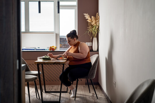 Size plus woman eating in the kitchen