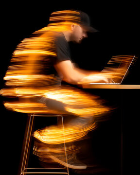 Motion Blurred Man Working on Laptop with Golden Light Streaks on Black Background, motion blur Business concept, motion bokeh background