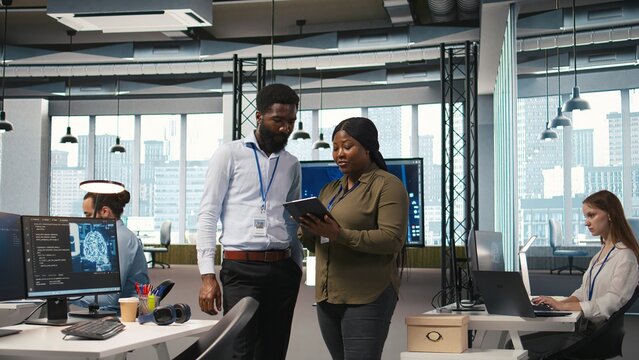 Startup office coworkers doing brainstorming, developing artificial intelligence models for business analytics. Team of engineers running simulations for AI driven forecasting, camera A