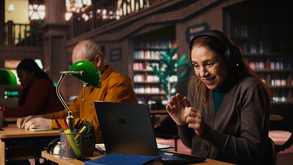 Woman listens to loud music on headset and disturbing other people in the library, senior man asking her to keep the volume low, breaking the library rules. Careless person singing.
