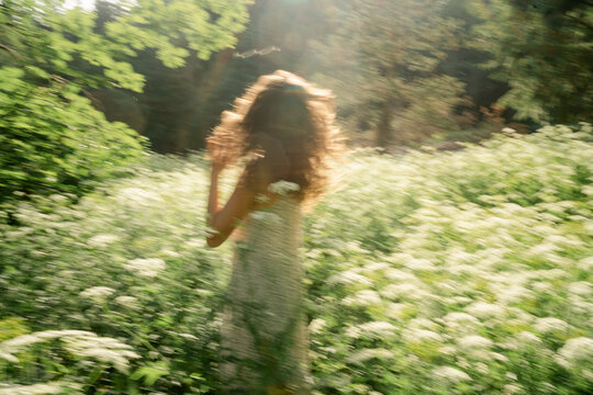 young woman dancing  in a field of wild flowers 