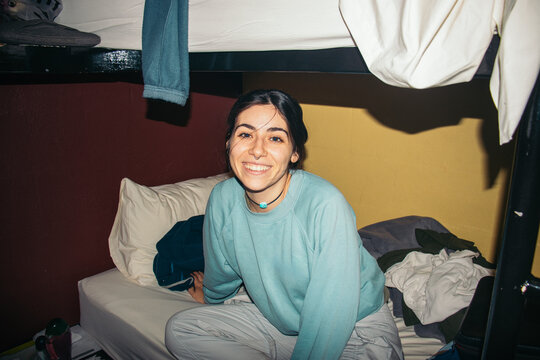 Flash-lit Smiling Woman in Hostel Bunk