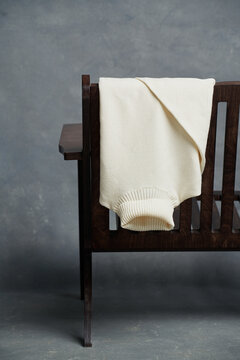 Cream Sweater Draped Over Wooden Chair