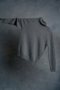 Hanging gray sweater against textured backdrop