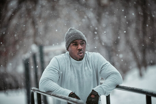 Man doing dips on bars during winter workout in snowy park