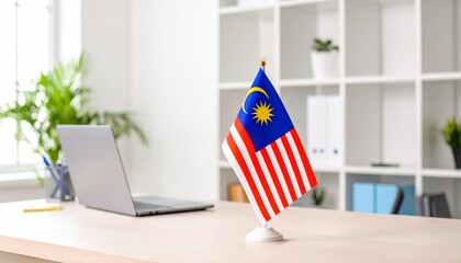 Malaysian flag on desk with laptop in bright office symbolizes national pride and Malaysian Independence Day concept