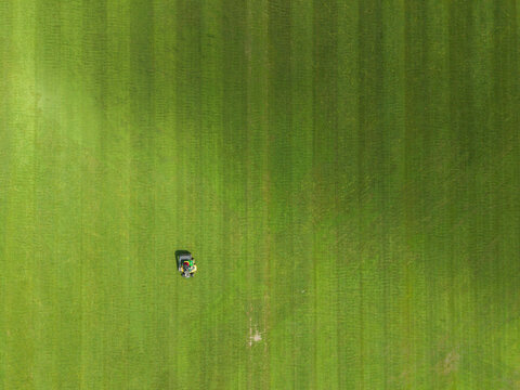Aerial View of Lawnmower Mowing Green Field Stripes