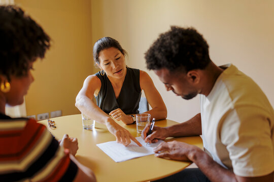Couple signing financial contract with advisor at bright office