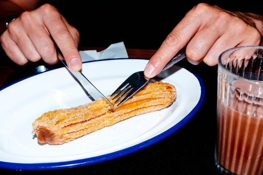 man is about to cut a churro filled with dulce de leche