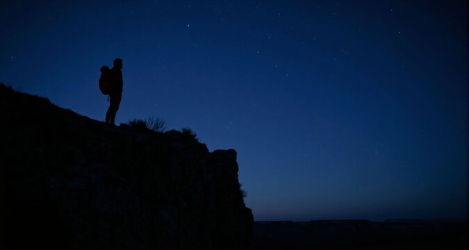 Solo hiker standing on cliff under starry sky