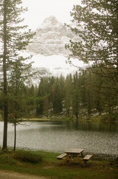 Lonely picnic table by alpine lake with snowy mountains behind