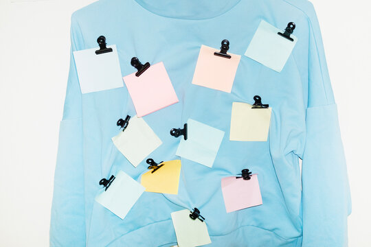 Blue shirt with colourful paper post it notes in it with golden clips